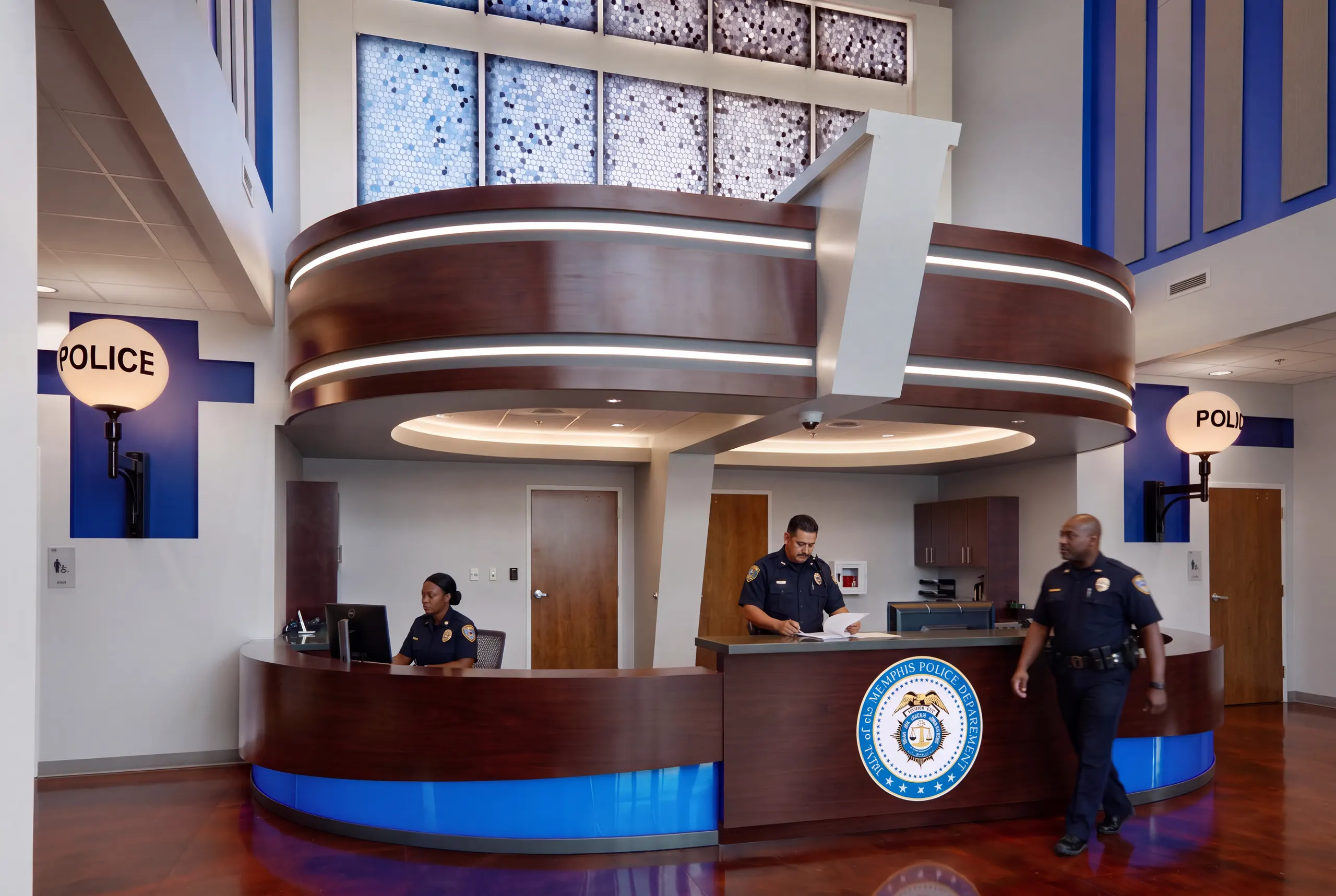 The front desk under a pierced metal screen, officers at the counter