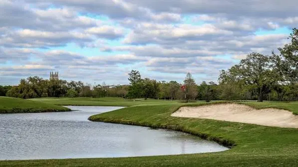A pond and bunker beneath a cloudy sky