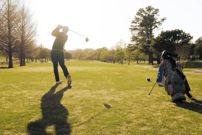 A golfer teeing off on an autumn afternoon