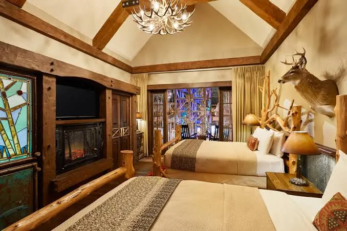 A suite with a stone fireplace, timber ceiling and a mounted deer