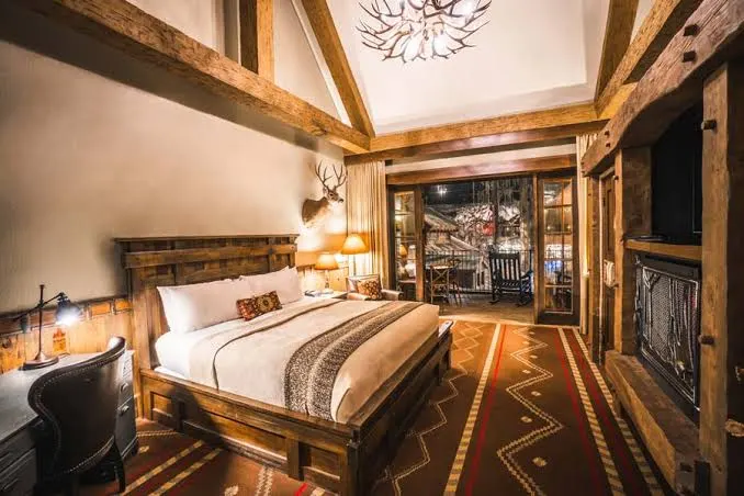 A guest room under timber beams and an antler chandelier