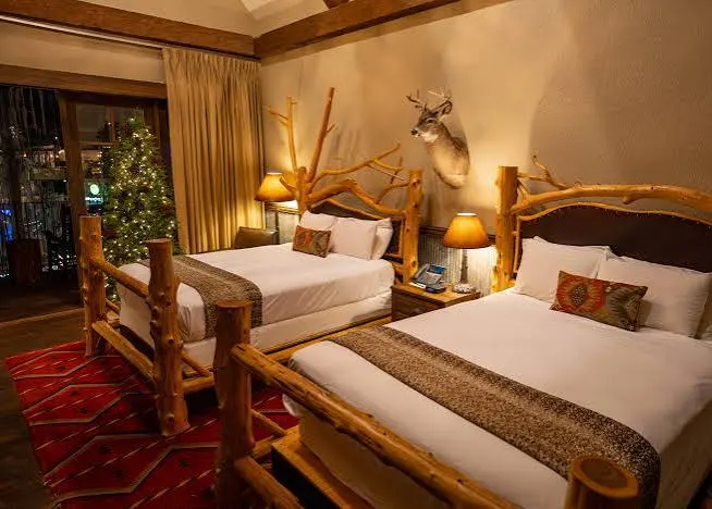 A guest room with log bedframes and a decorated tree