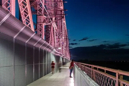The walkway lit at dusk, the truss glowing overhead