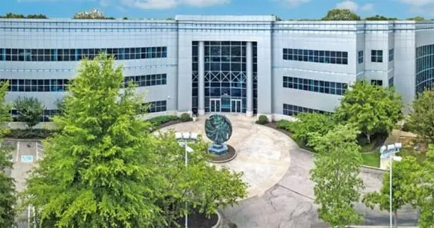 The office building's curved glass entrance and courtyard sculpture
