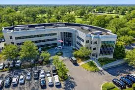 Aerial view of the building and its parking court among trees