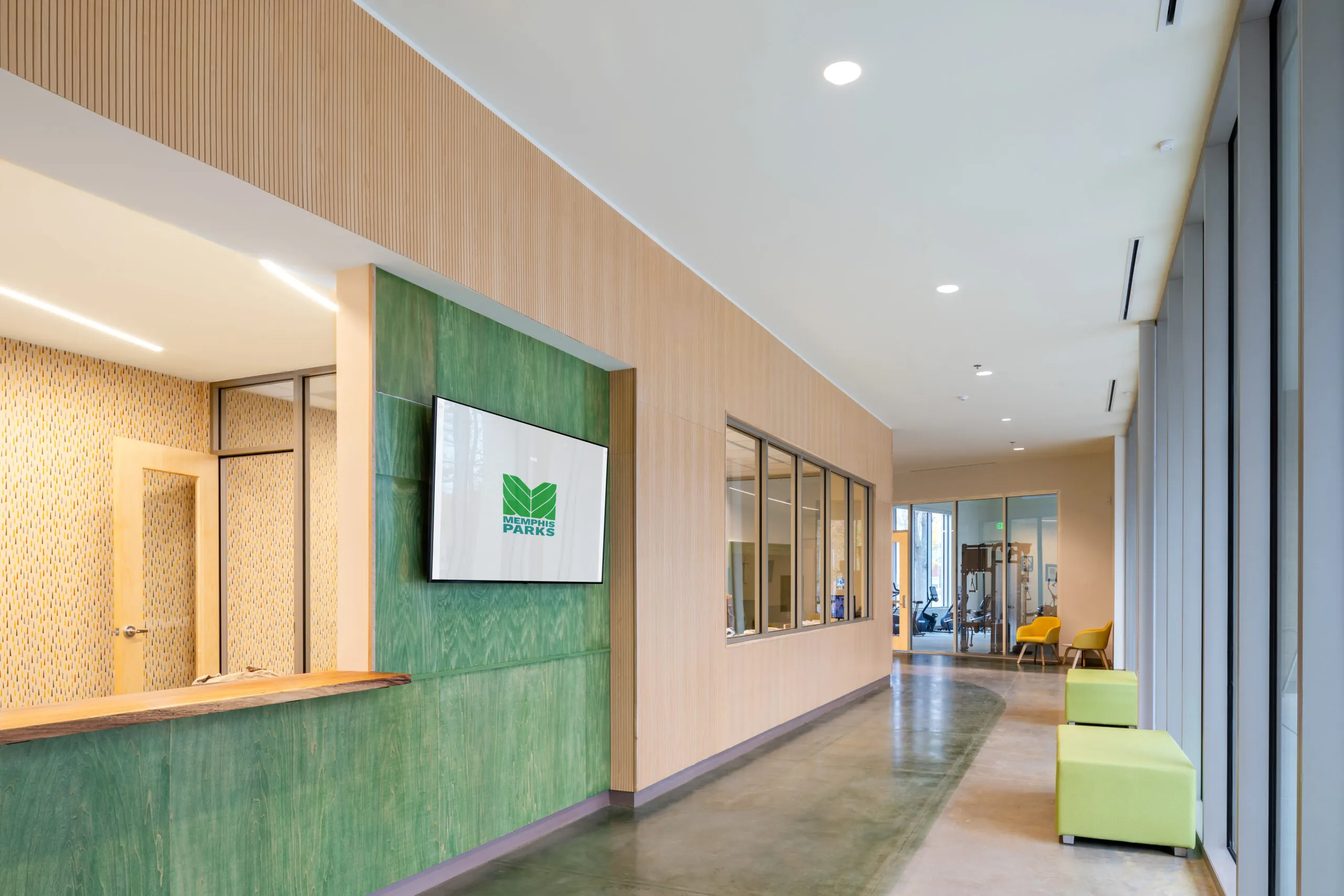 A corridor with wood slat walls, a green tile panel and lime seating