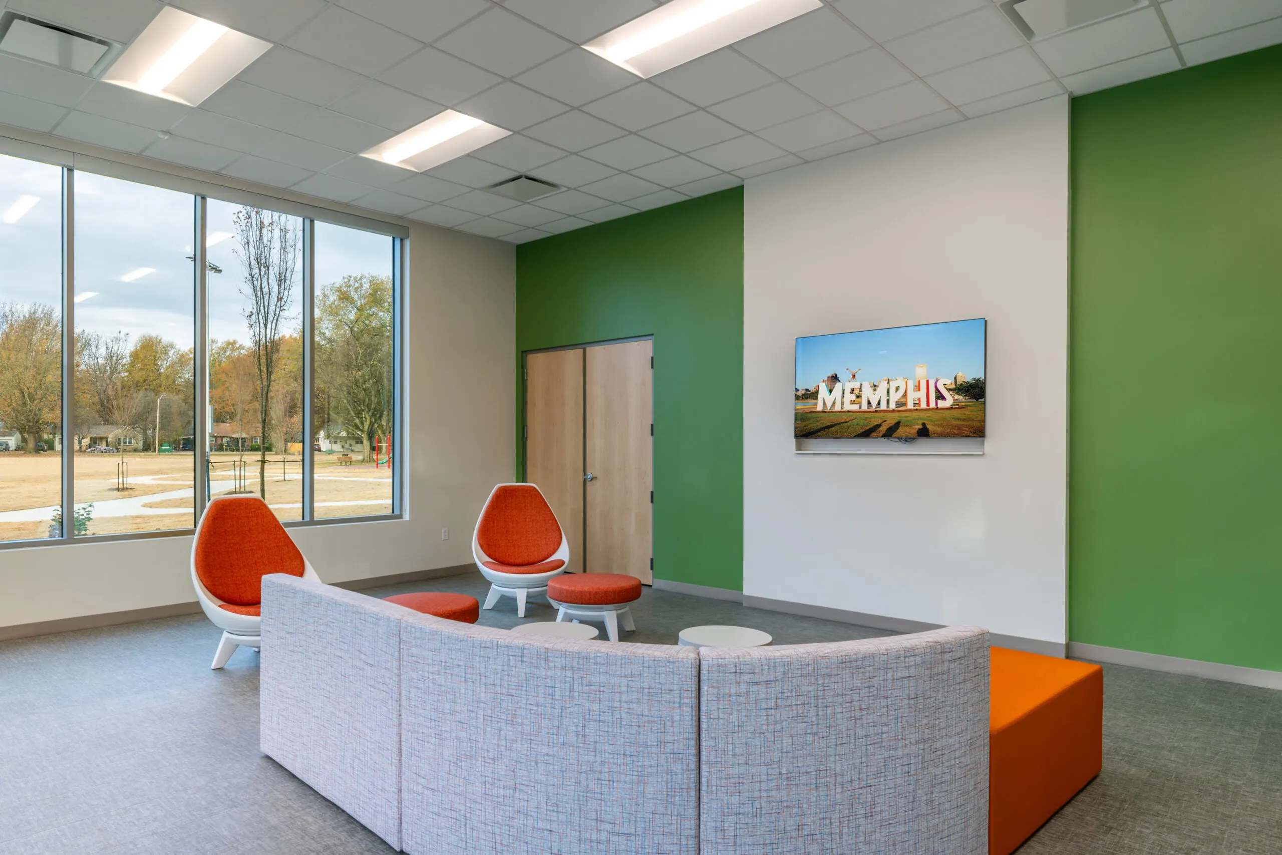A lounge with orange egg chairs beside tall windows