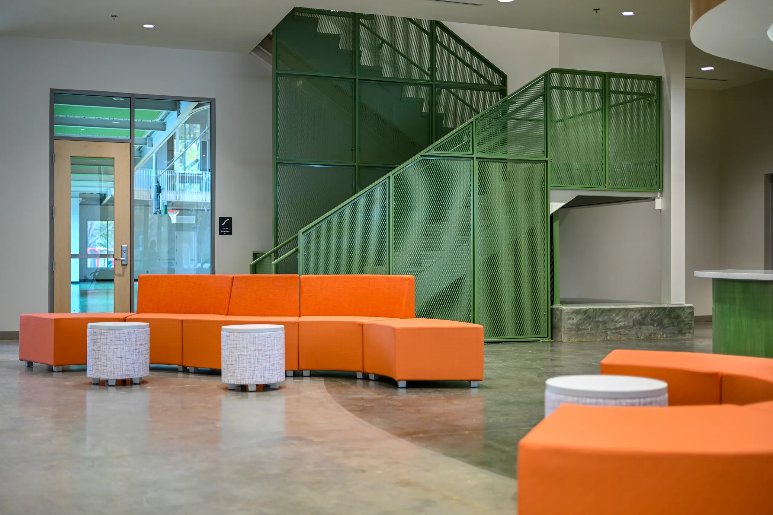 Orange lounge seating beside a green mesh stair
