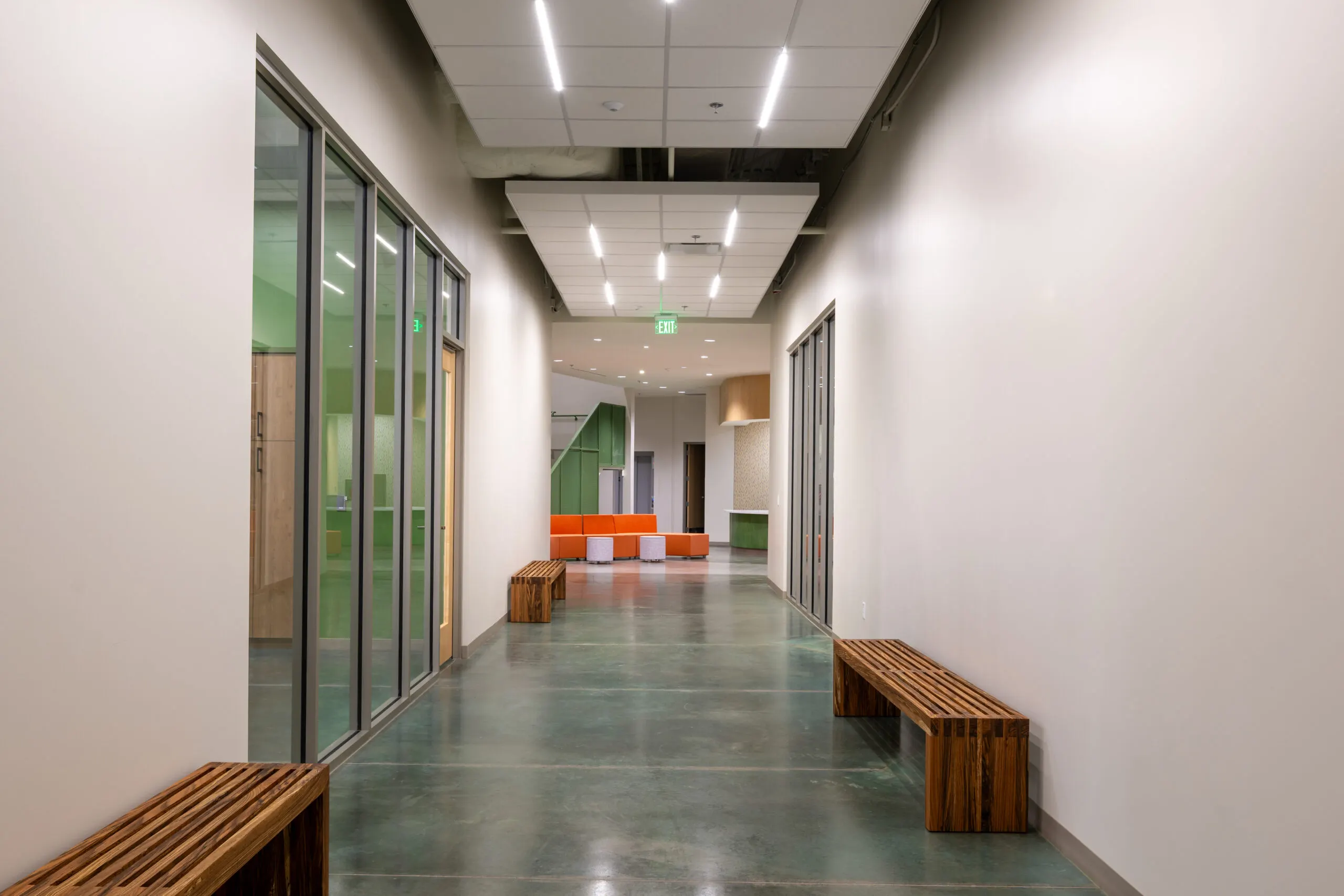 A corridor with a timber bench along a glass wall