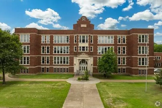 A historic brick school and its front walk from above