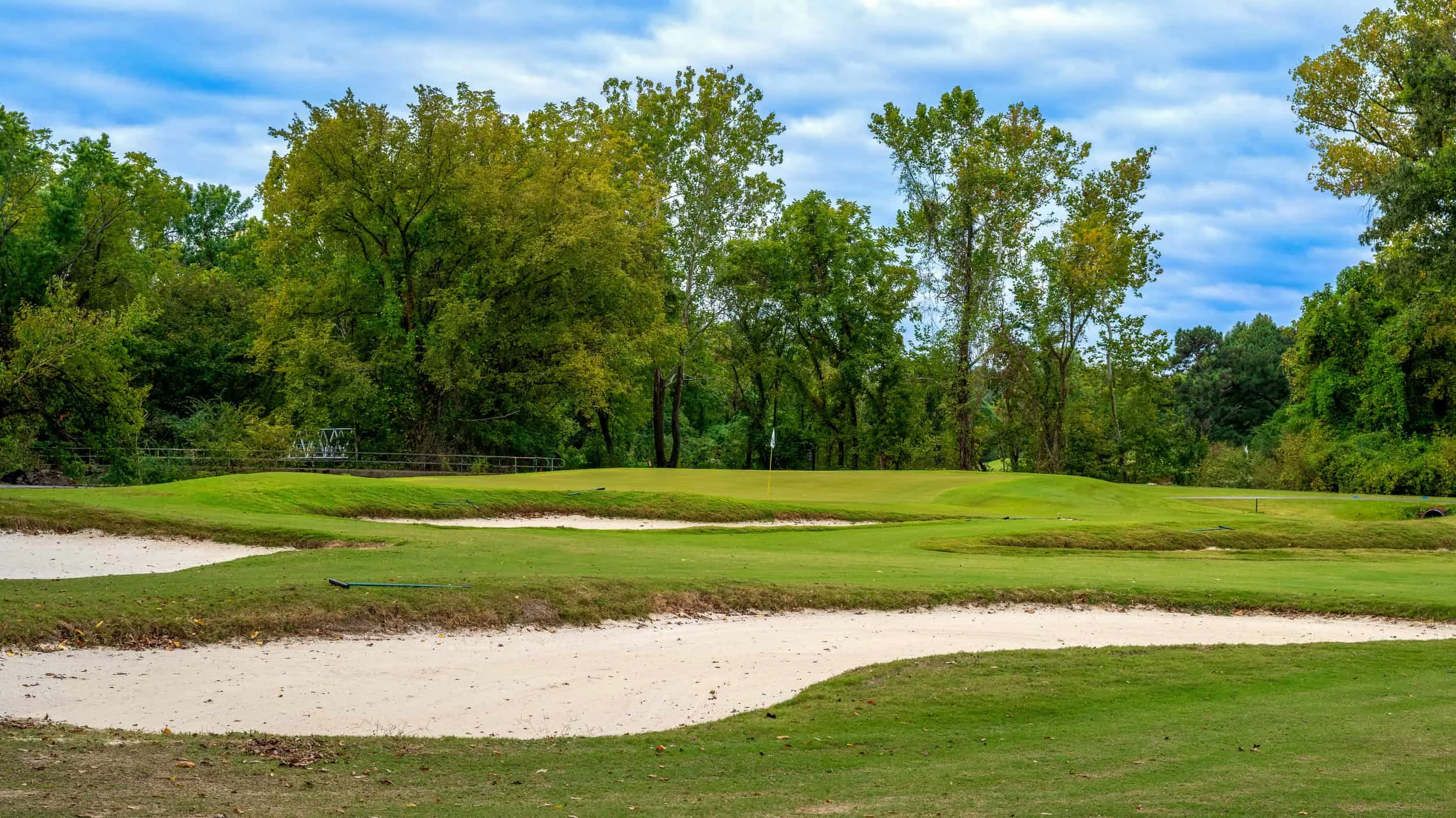 A white sand bunker at the edge of the tree line