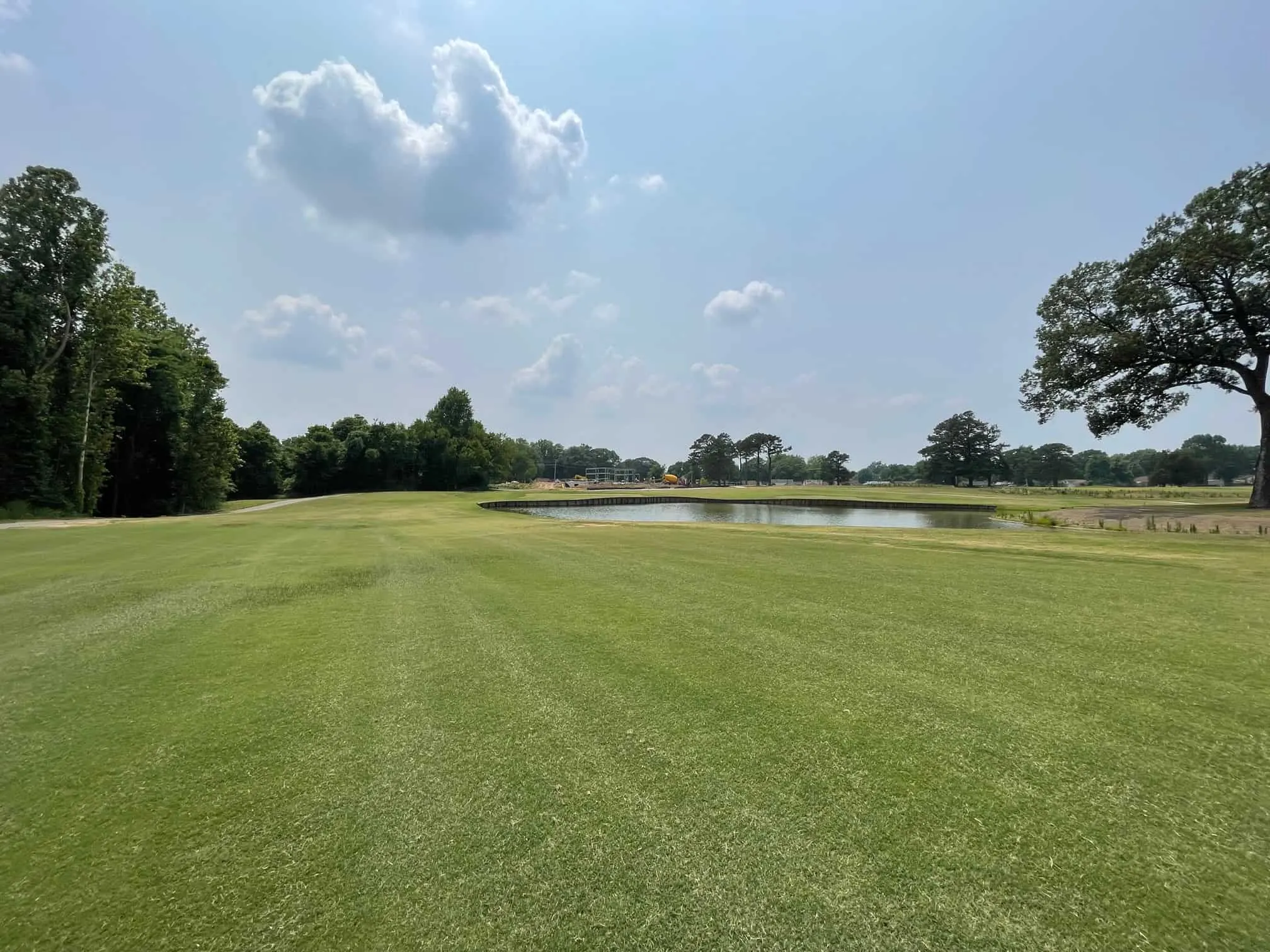 A mown fairway running toward a pond