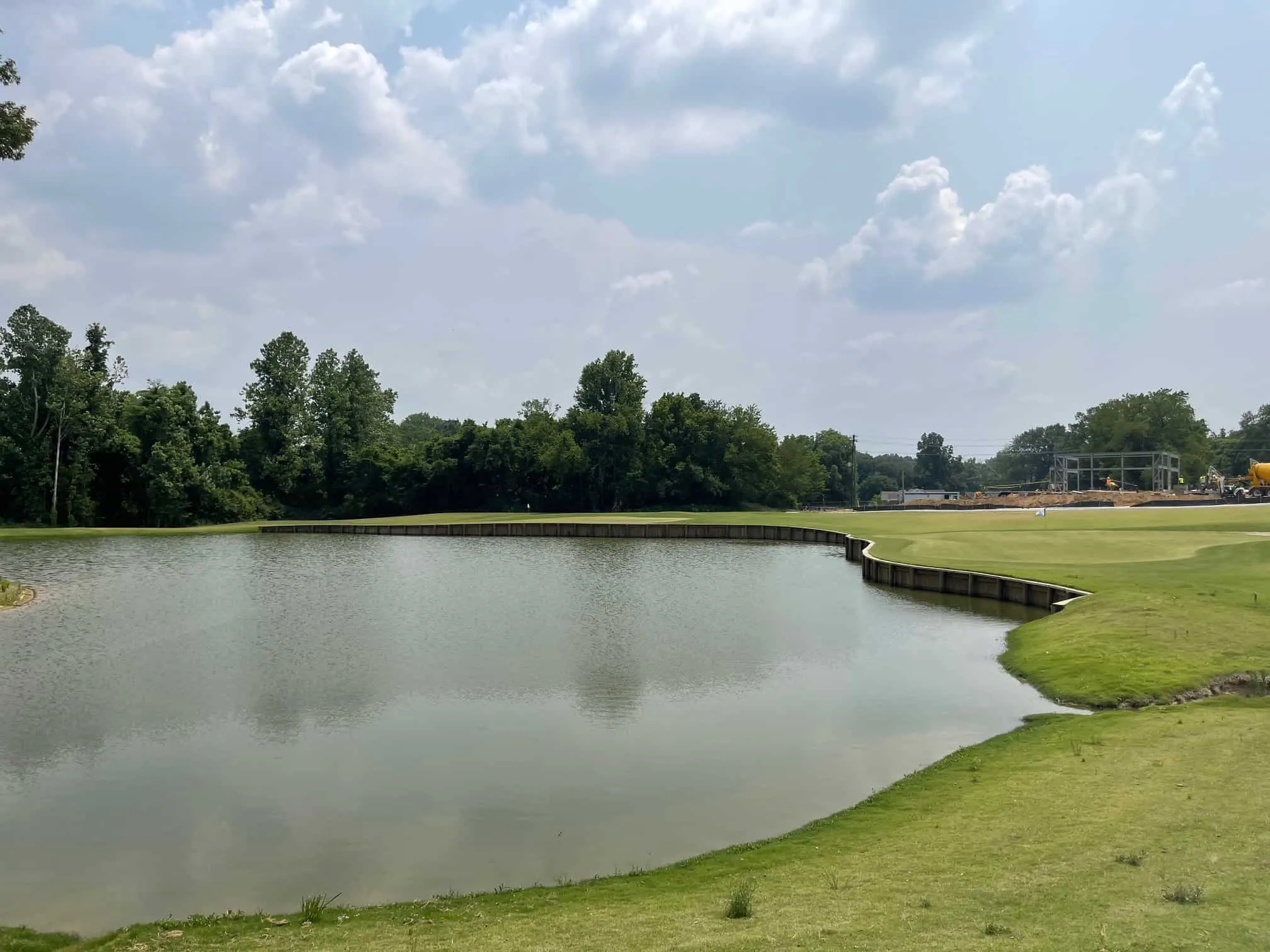 A pond edged with timber bulkheads under summer clouds