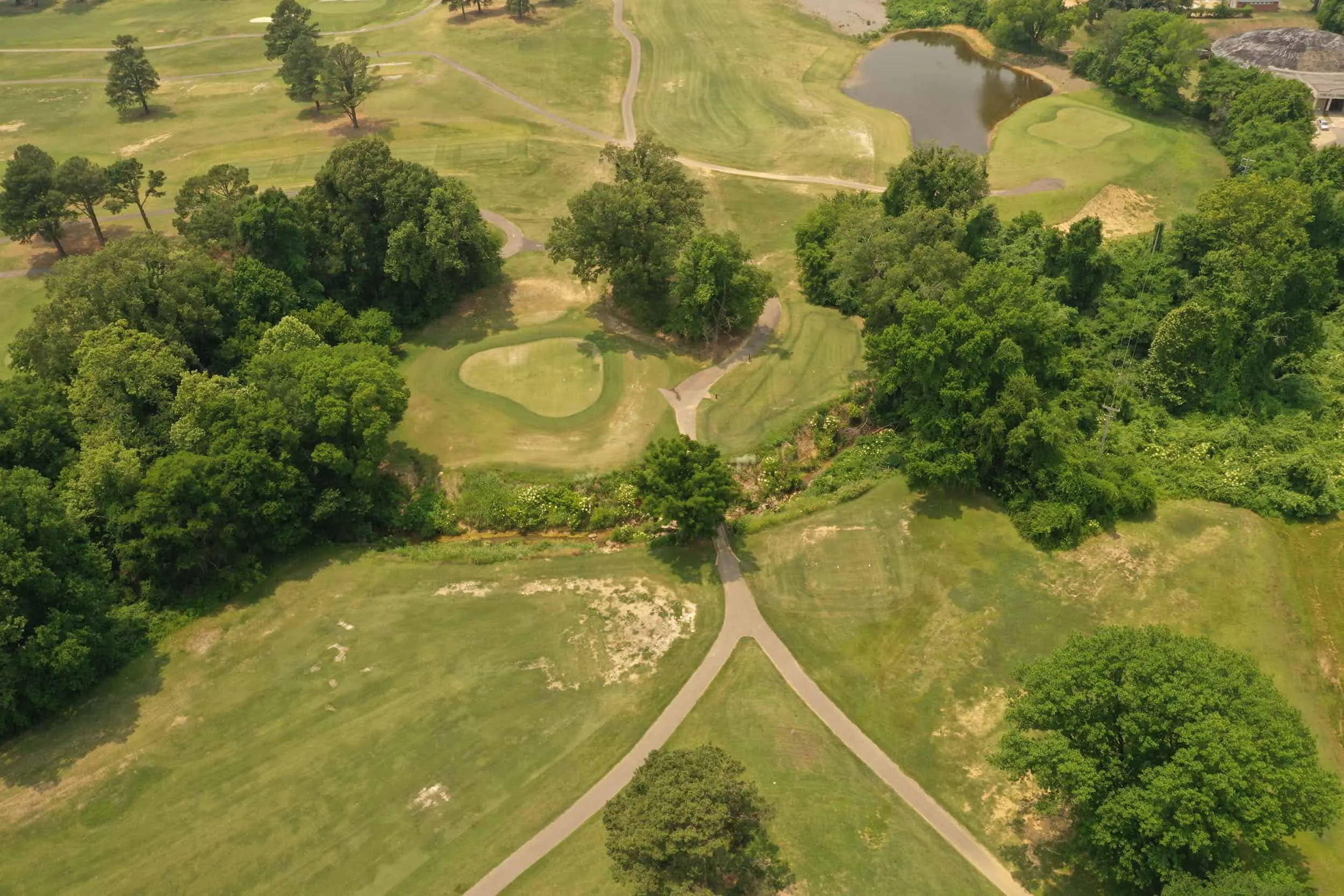 Aerial view of greens and bunkers among mature trees