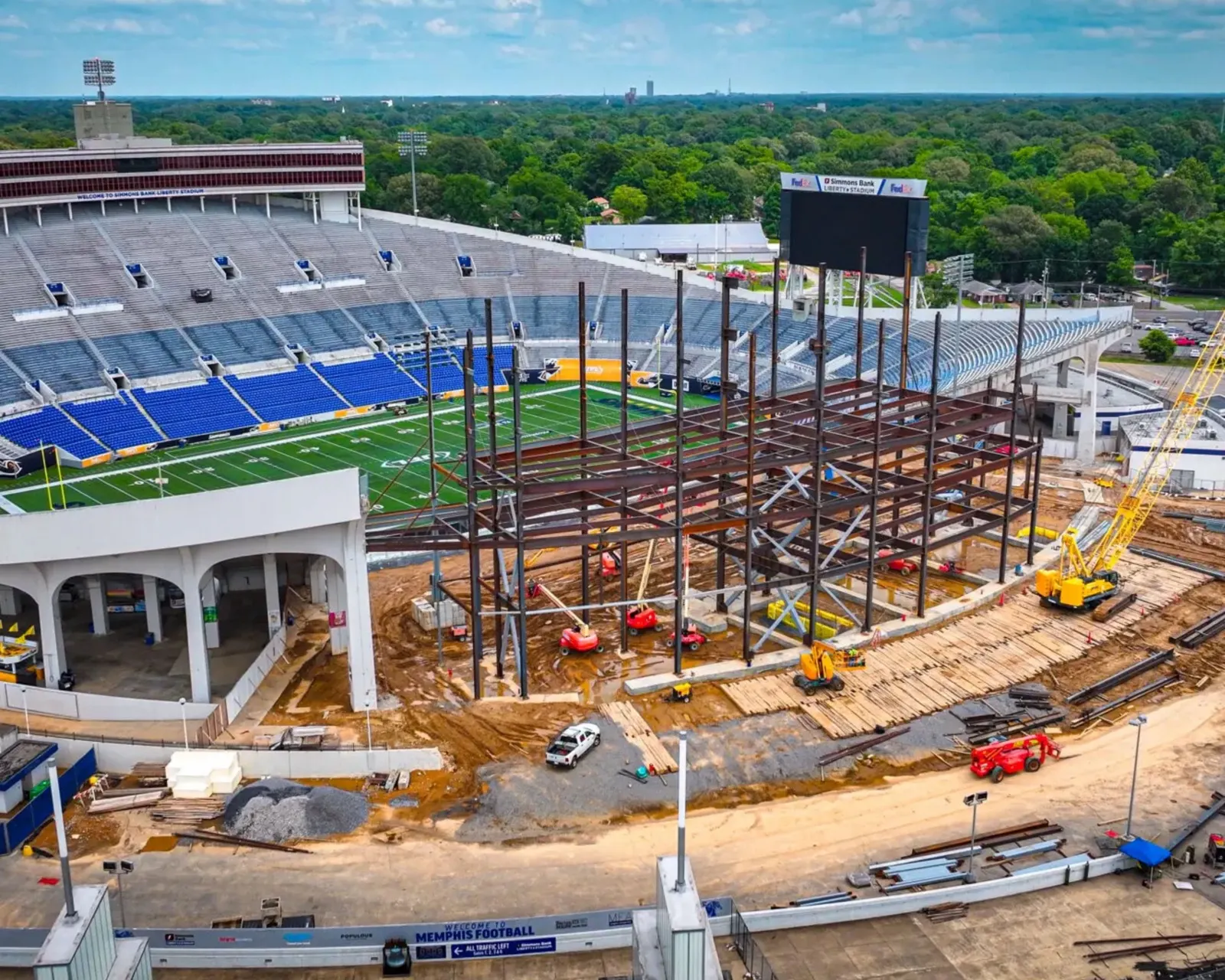 The west side tower under construction, steel rising beside the stands