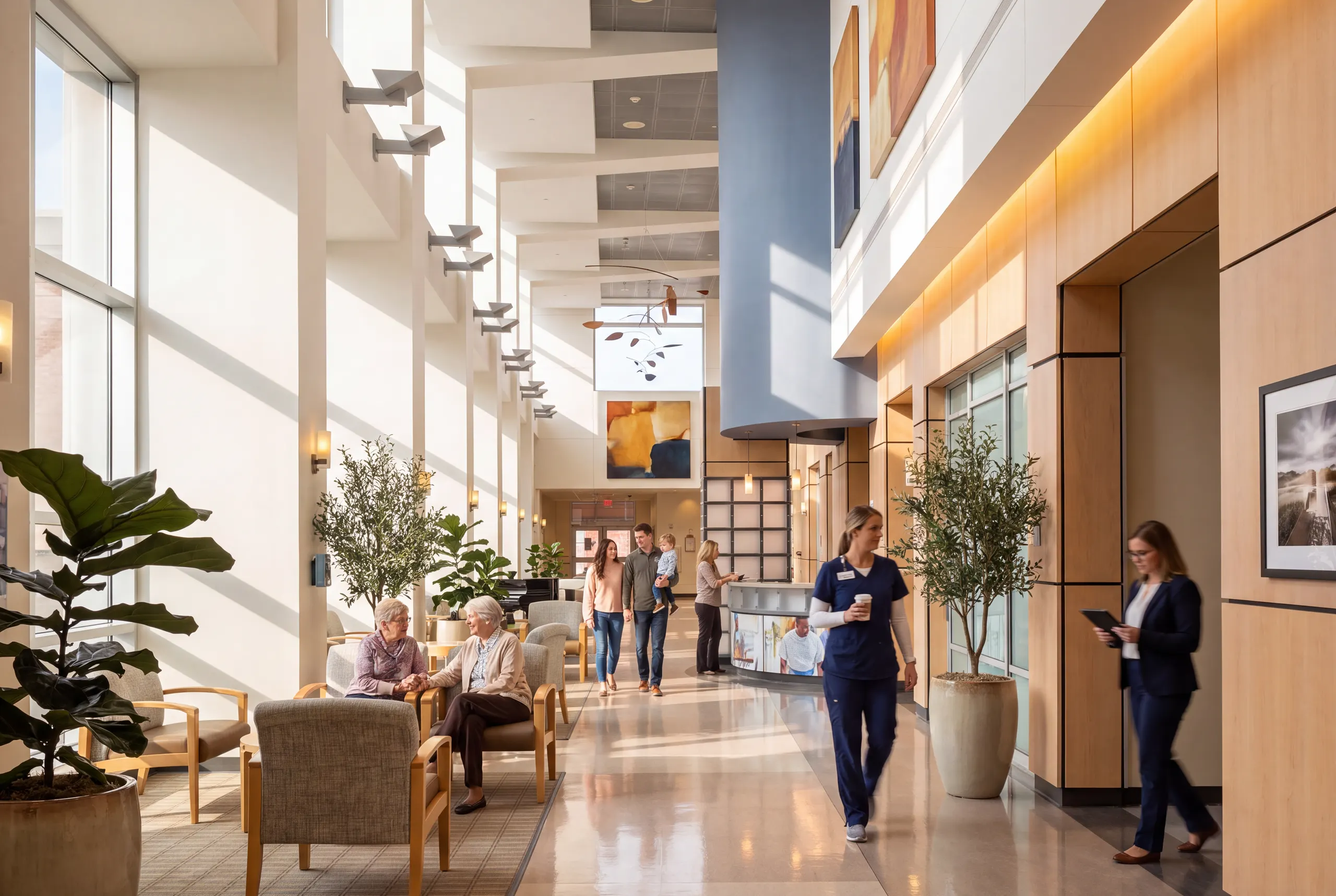 A daylit concourse with seating, planters and staff passing through