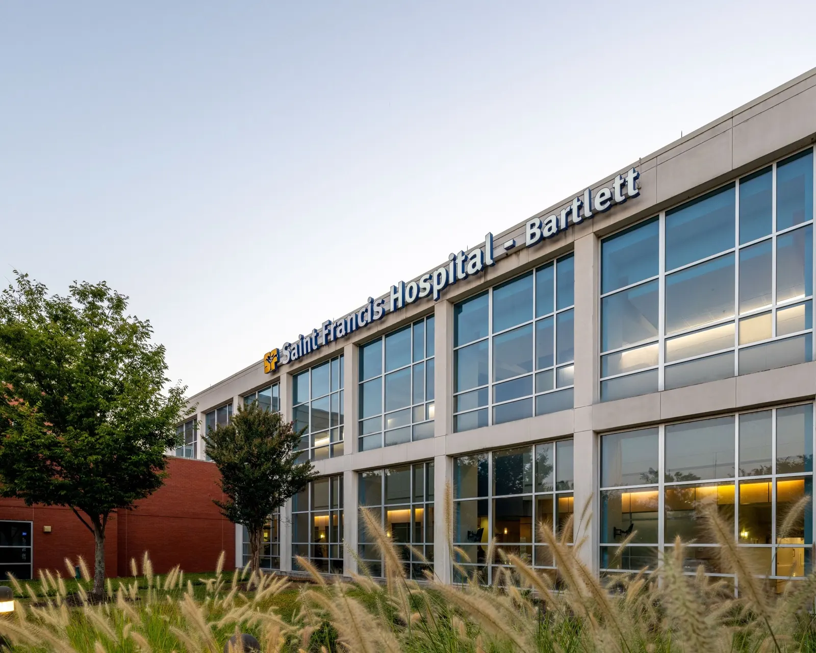 The hospital's entrance facade and signage behind ornamental grasses