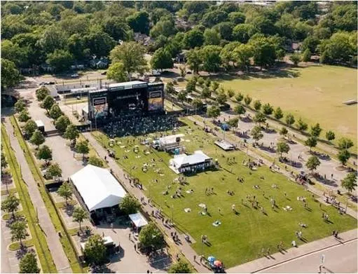 A concert crowd on the lawn beside the lane