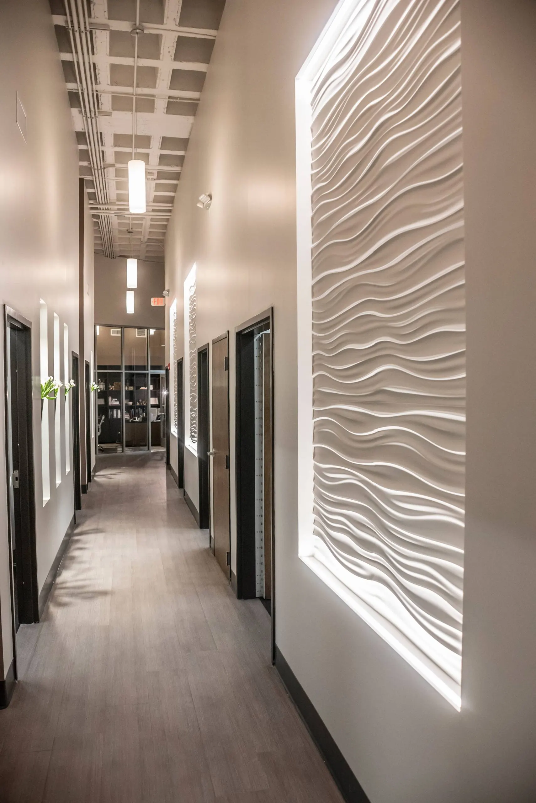 A corridor lit by a backlit sculpted wall panel